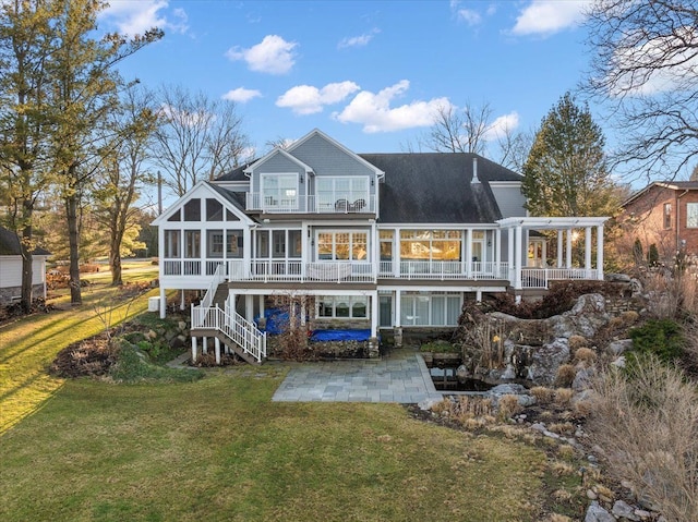 rear view of property with a patio, a lawn, and a sunroom