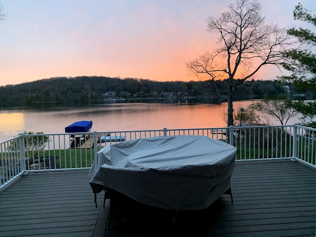 deck at dusk with a water view and area for grilling