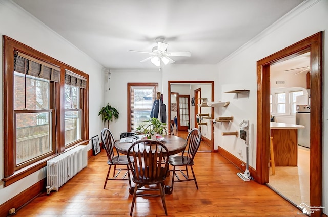 dining space with light wood-type flooring, radiator, ornamental molding, and ceiling fan