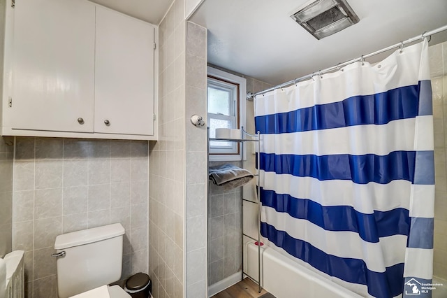 bathroom with hardwood / wood-style floors, toilet, tile walls, and shower / bath combo with shower curtain