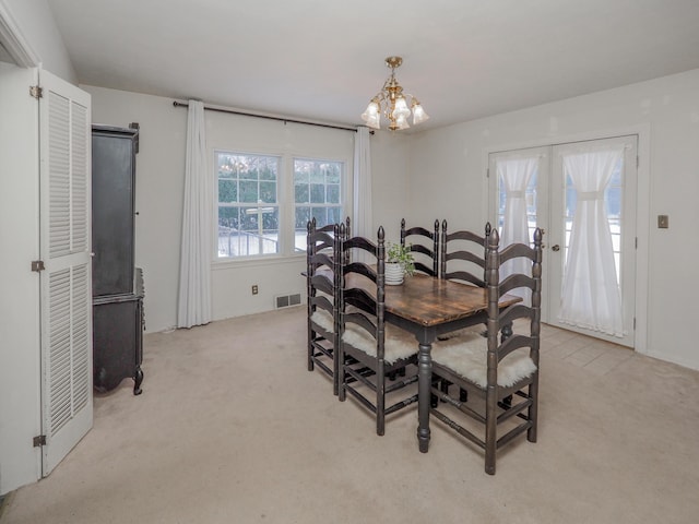 dining room with french doors, light colored carpet, and an inviting chandelier