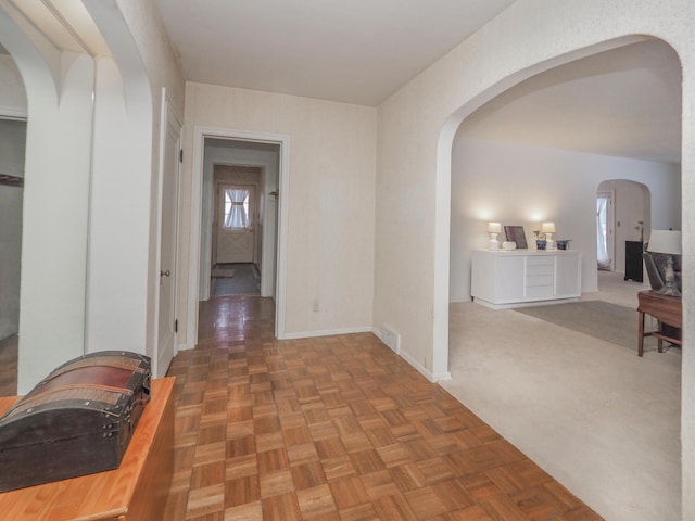 hall featuring dark parquet floors and a healthy amount of sunlight