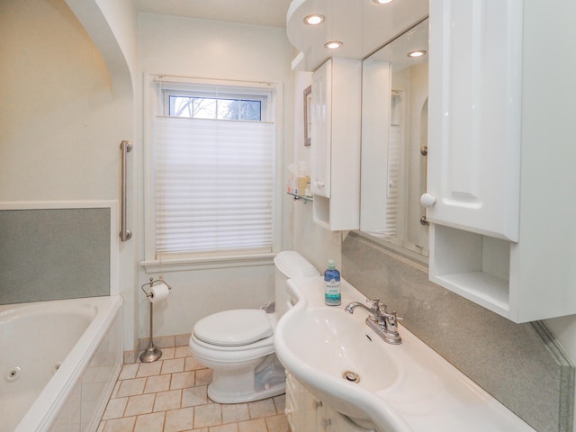 bathroom with tiled bath, tile patterned flooring, vanity, and toilet