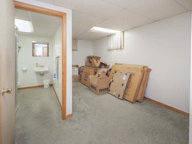 basement featuring a paneled ceiling and light carpet