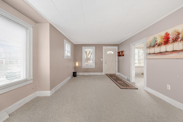 foyer with crown molding and light carpet