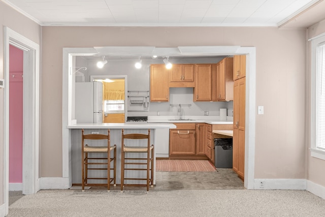 kitchen with a wealth of natural light, sink, a breakfast bar area, ornamental molding, and white fridge