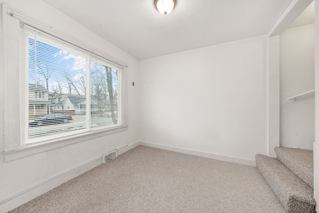 carpeted empty room featuring a textured ceiling