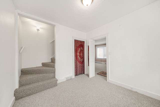 stairway featuring carpet and a textured ceiling