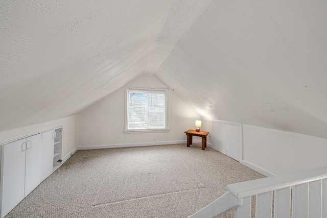 additional living space featuring lofted ceiling, light carpet, and a textured ceiling