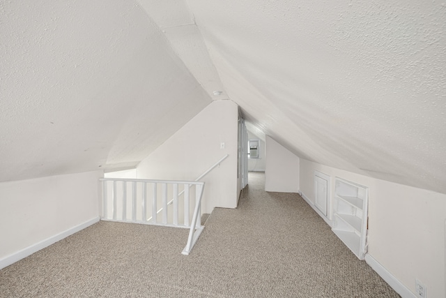 bonus room featuring lofted ceiling, light colored carpet, and a textured ceiling