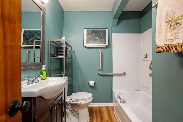 bathroom with hardwood / wood-style floors, vanity, a bath, and toilet