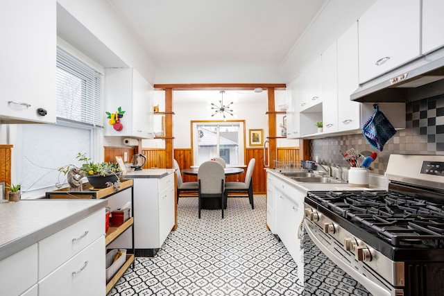 kitchen featuring backsplash, white cabinets, sink, gas range, and extractor fan