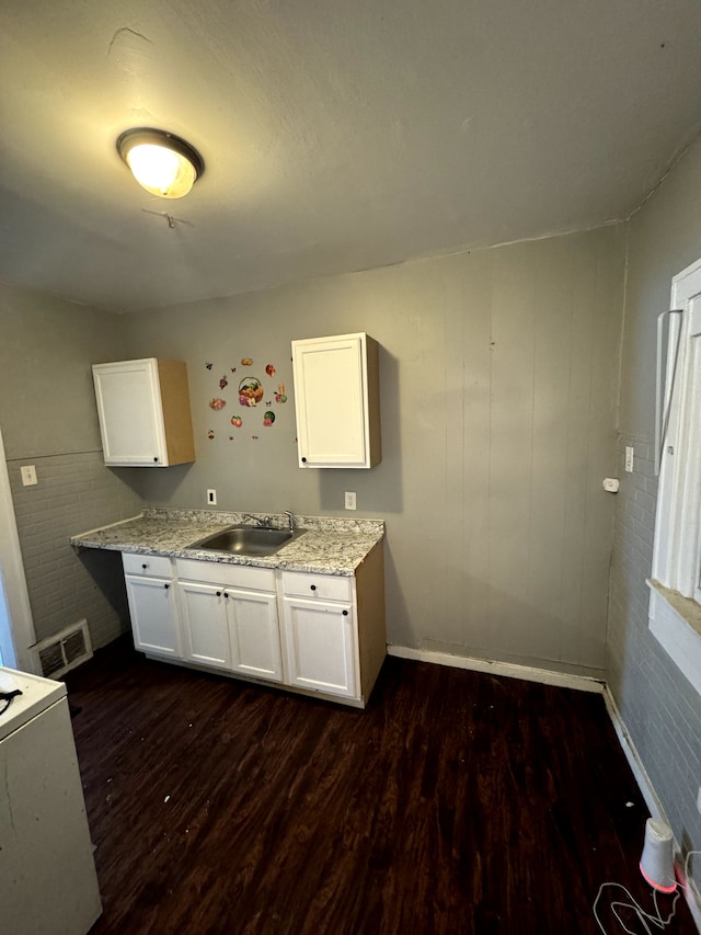 kitchen with white cabinetry, light stone countertops, sink, and dark wood-type flooring