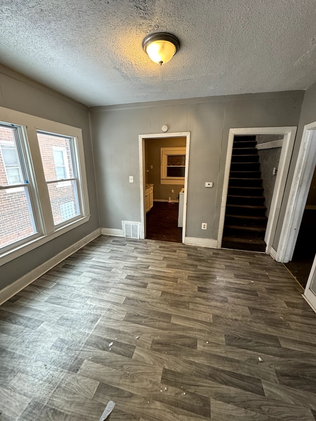 unfurnished room featuring a textured ceiling and dark hardwood / wood-style flooring