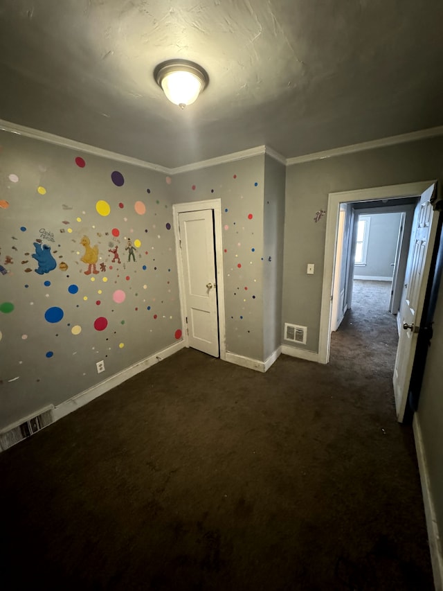 unfurnished room featuring crown molding and dark colored carpet