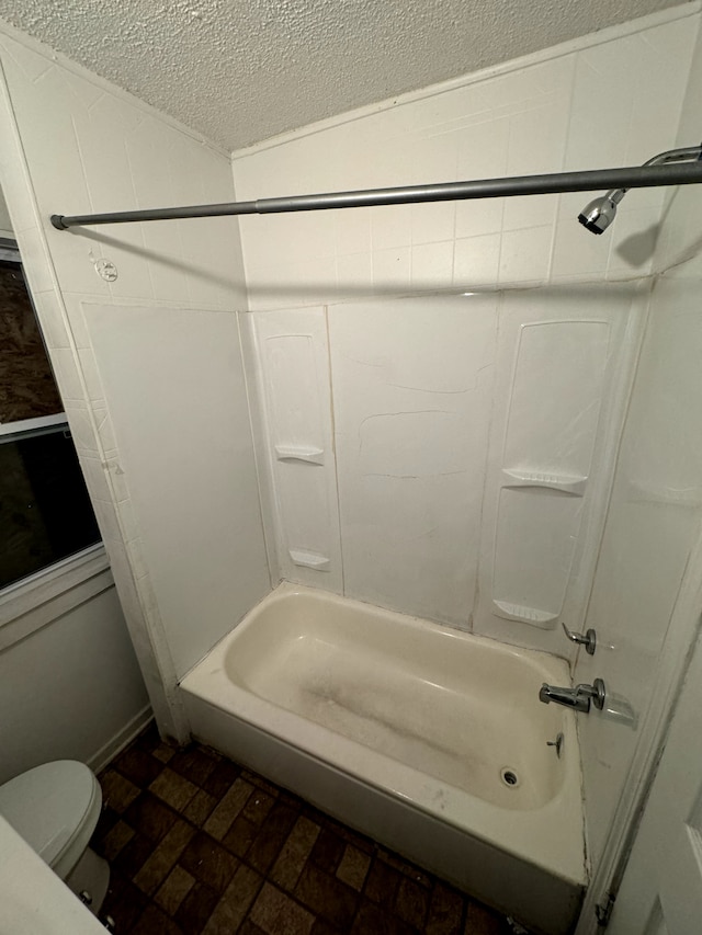 bathroom with toilet, bathing tub / shower combination, and a textured ceiling