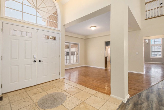 entrance foyer with light wood finished floors, a high ceiling, and baseboards