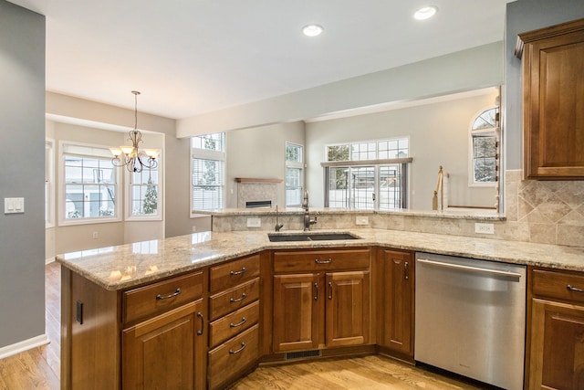 16073 Silverwood Dr, Fenton, MI 48430 - kitchen featuring a fireplace, brown cabinetry, decorative backsplash, dishwasher, and a sink