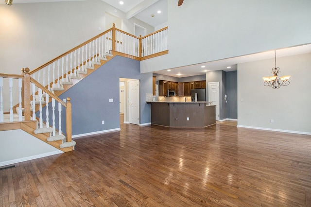 unfurnished living room featuring visible vents, baseboards, dark wood-style floors, stairway, and an inviting chandelier