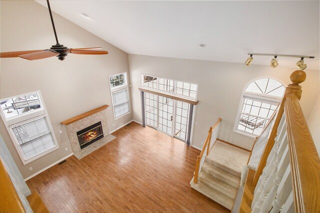 living room featuring ceiling fan, a tiled fireplace, vaulted ceiling, and hardwood / wood-style floors