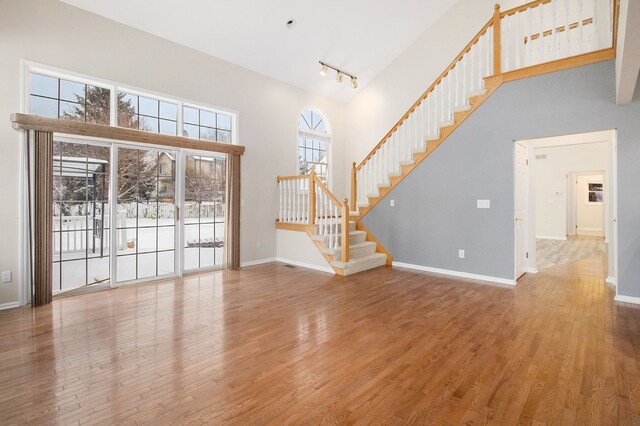 unfurnished living room with a towering ceiling and hardwood / wood-style floors