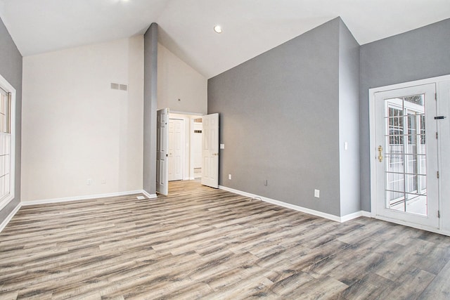 spare room with light wood-type flooring, plenty of natural light, and high vaulted ceiling