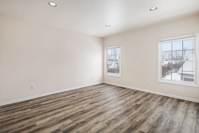 unfurnished room featuring dark wood-type flooring and plenty of natural light