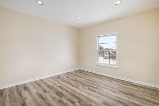 unfurnished room featuring recessed lighting, wood finished floors, and baseboards