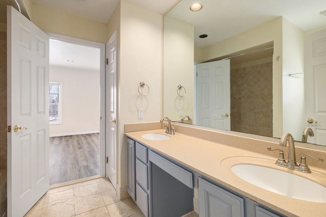 bathroom featuring double vanity, a sink, stone tile flooring, and recessed lighting