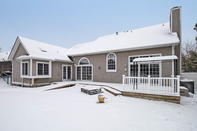 snow covered rear of property featuring a wooden deck and cooling unit