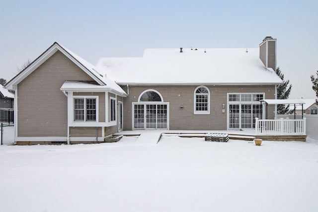 snow covered back of property featuring a wooden deck