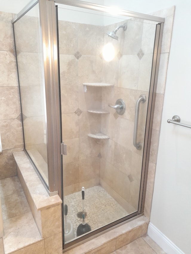 bathroom featuring a stall shower, tile patterned flooring, and baseboards