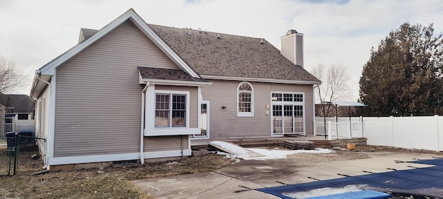 back of house with a fenced in pool, roof with shingles, a patio, a chimney, and fence