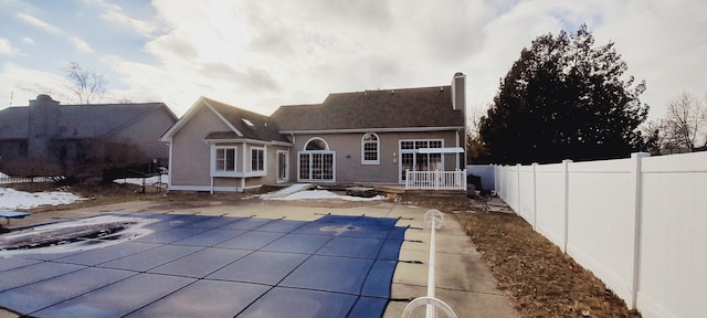 rear view of property with a fenced in pool, stucco siding, fence, and a patio