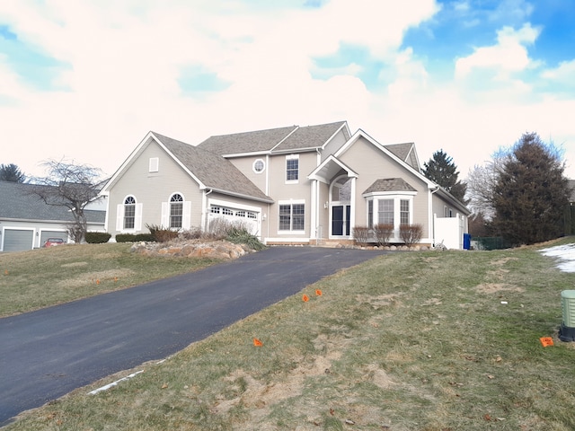 traditional home featuring aphalt driveway and a front lawn