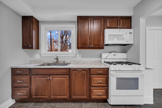 kitchen featuring white appliances, light stone countertops, and sink