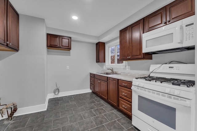 kitchen featuring white appliances, light stone countertops, sink, and dark tile patterned flooring