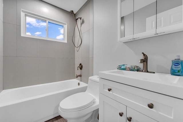 full bathroom featuring tiled shower / bath, vanity, and toilet