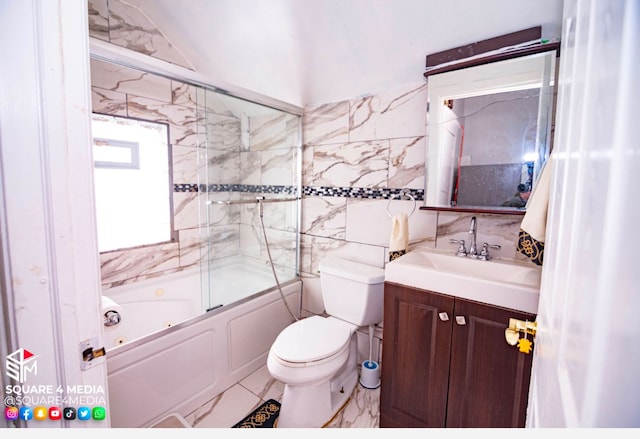 full bathroom with toilet, vanity, tile walls, and shower / bath combination with glass door