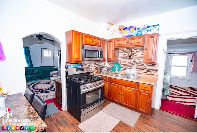 kitchen with appliances with stainless steel finishes, decorative backsplash, sink, dark hardwood / wood-style floors, and ceiling fan