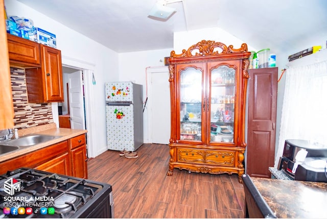 kitchen featuring range with gas stovetop, dark wood-type flooring, decorative backsplash, sink, and stainless steel refrigerator