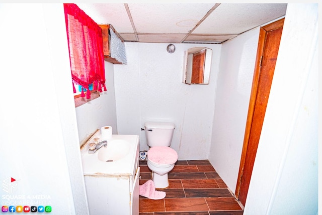 bathroom featuring toilet, a drop ceiling, and vanity