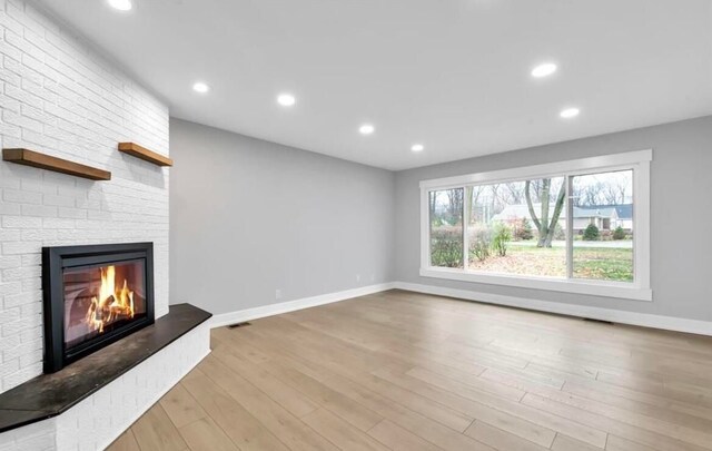 unfurnished living room featuring a fireplace and light hardwood / wood-style flooring