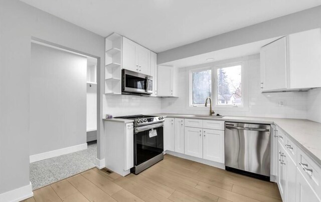 kitchen featuring white cabinets, sink, decorative backsplash, light hardwood / wood-style floors, and stainless steel appliances