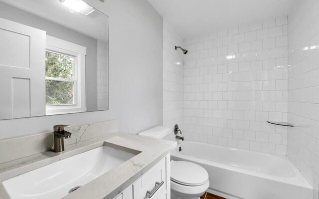 full bathroom featuring vanity, tiled shower / bath combo, and toilet