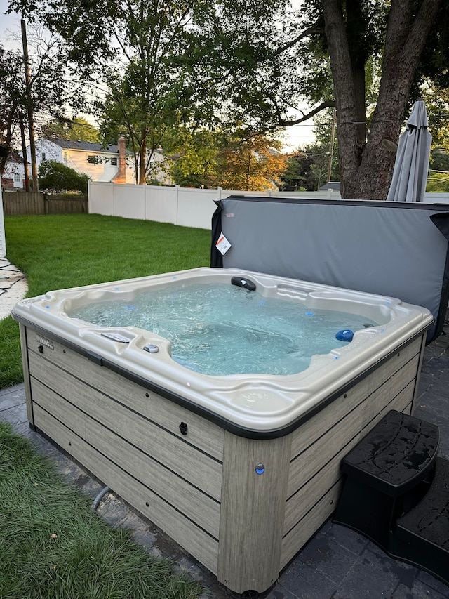 view of swimming pool with a lawn and a hot tub