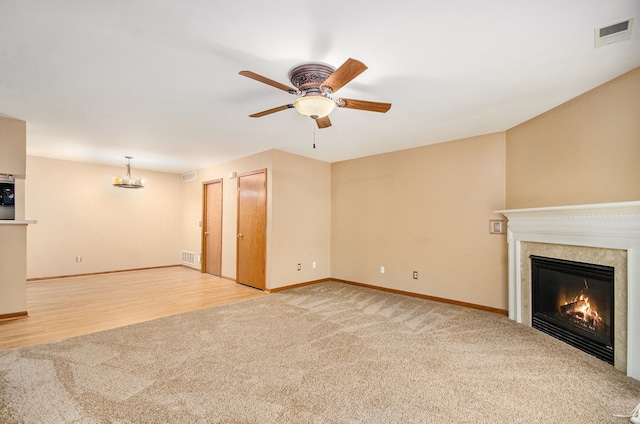 unfurnished living room featuring light colored carpet and ceiling fan with notable chandelier