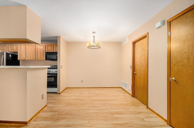 kitchen featuring stainless steel fridge, light brown cabinetry, gas range gas stove, decorative light fixtures, and light hardwood / wood-style floors