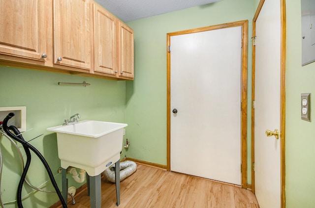 clothes washing area with cabinets, hookup for a washing machine, light wood-type flooring, and sink