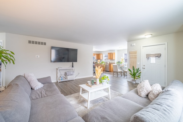 living room featuring visible vents, baseboards, and light wood finished floors